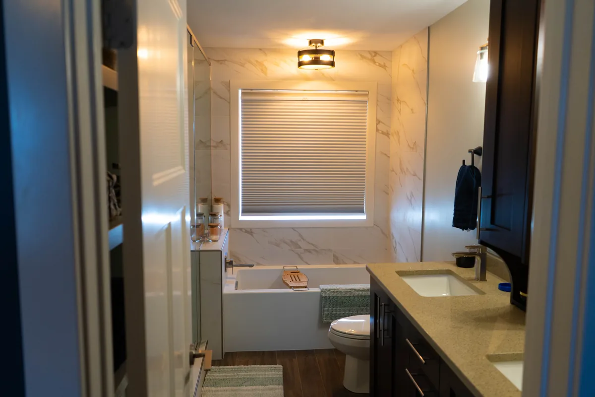 Renovated bathroom with bathtub, tiled shower, vanity and natural window light